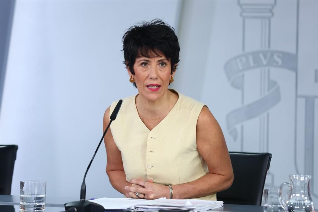 Ministra del Gobierno durante una rueda de prensa, sentada ante un micrófono y documentación.